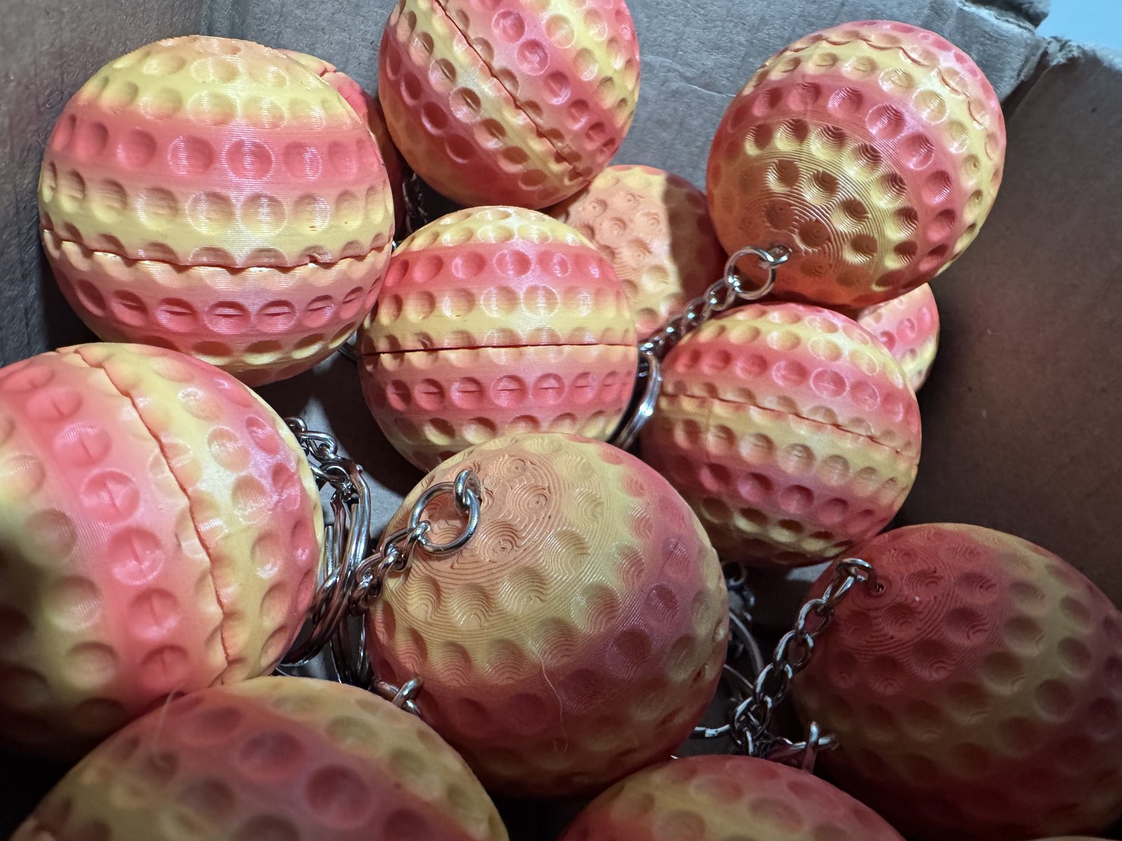 Golf-ball stash keychains, printed in pink and gold.