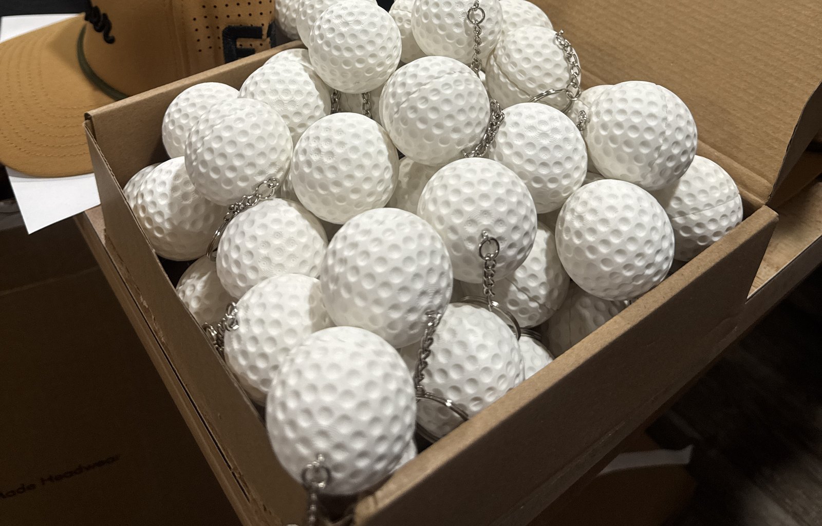 White stash-ball keychains beside the hats. Order details removed.